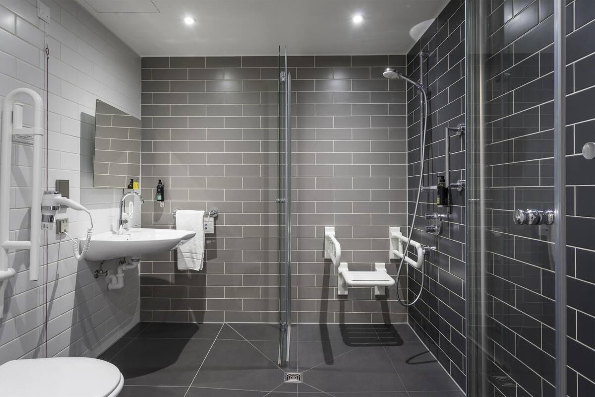 Une salle de bain moderne dotée d’une douche à parois de verre, d’un lavabo et de toilettes.