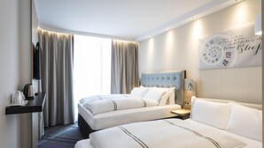 Habitación de hotel con dos camas, televisión, reloj y ventana con cortinas.