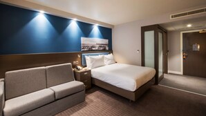 Una camera d'albergo con un letto, un divano, un comodino e un quadro appeso al muro.