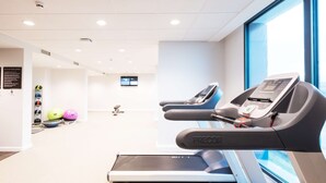 Una palestra con tapis roulant, palle da ginnastica e un display digitale.