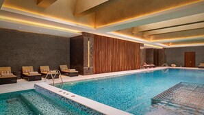 An indoor swimming pool with lounge chairs and a wooden wall.