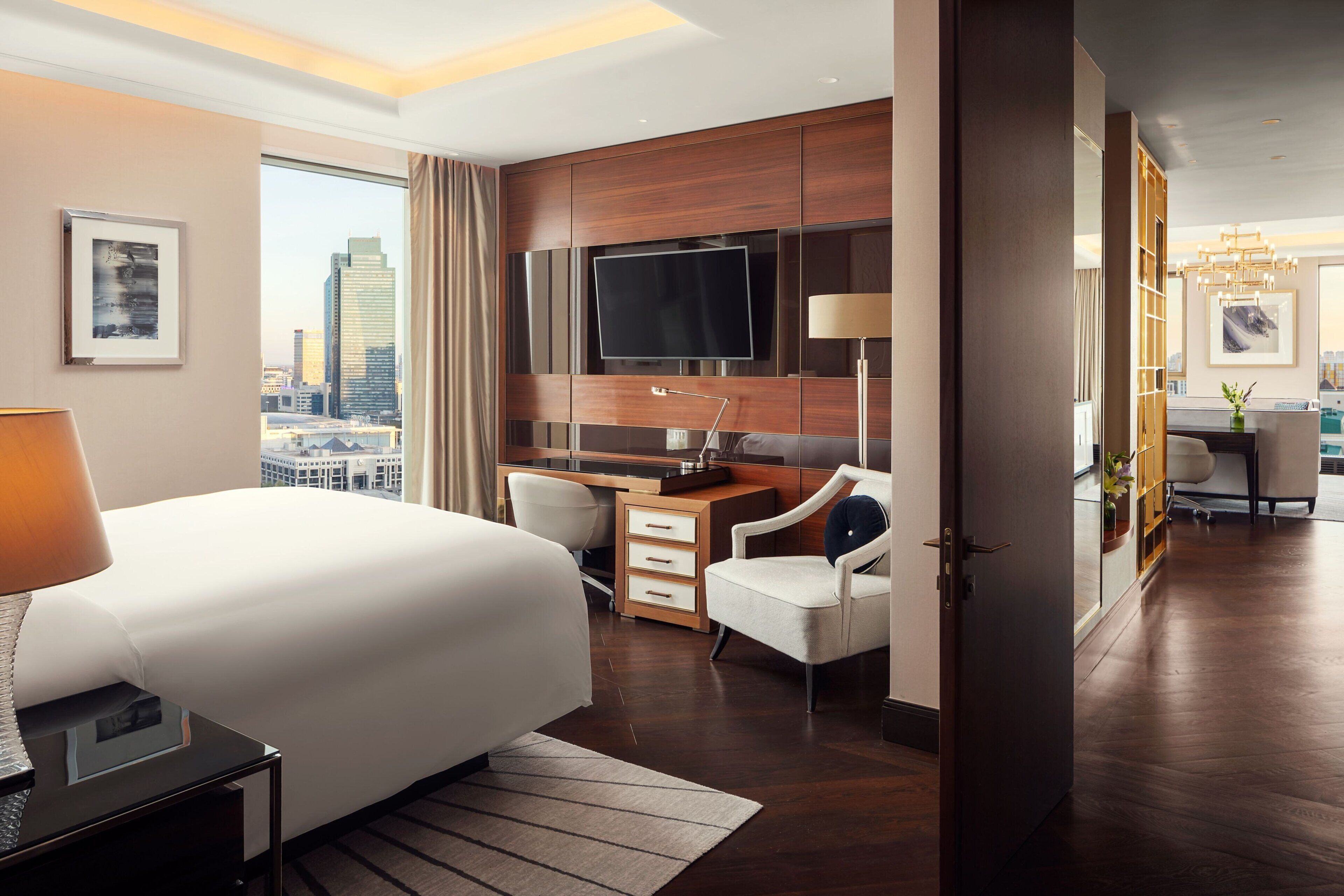Quarto de hotel moderno com uma cama grande, uma escrivaninha, uma televisão e vista para a cidade.