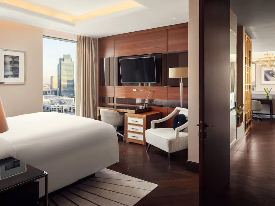 Quarto de hotel moderno com uma cama grande, uma escrivaninha, uma televisão e vista para a cidade.