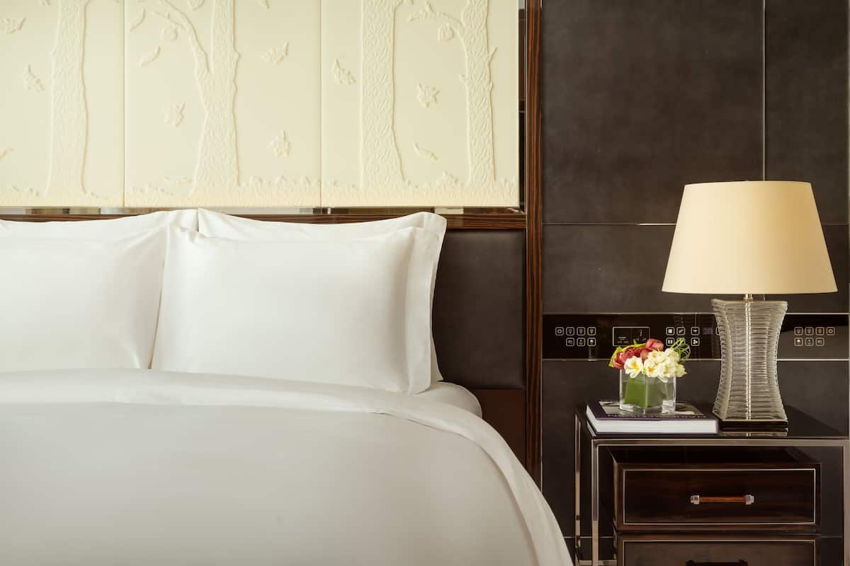 Ein Hotelzimmer mit einem großen Bett, einem Nachttisch mit Lampe und einer dekorativen Wandverkleidung.