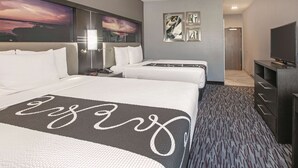 Une chambre d’hôtel avec deux lits, une télévision et des œuvres d’art accrochées aux murs.