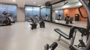 Une salle de sport équipée de tapis de course, de vélos elliptiques et de matériel de musculation.