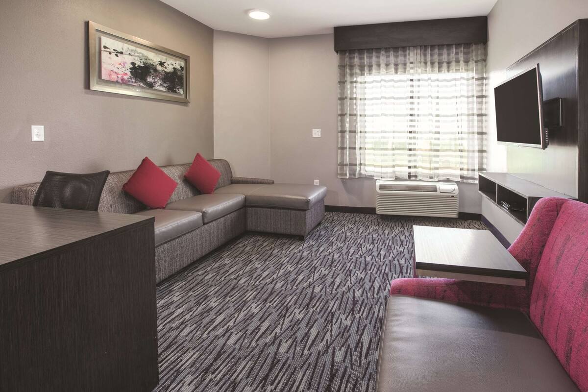 Een moderne woonkamer met een hoekbank, een flatscreen televisie en een kamerbreed tapijt met een patroon.