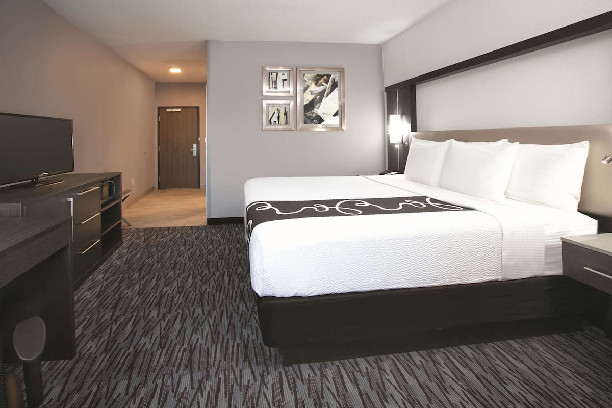 Een hotelkamer met een groot bed, een flatscreen-tv, een bureau met lades en een vloerbedekking.
