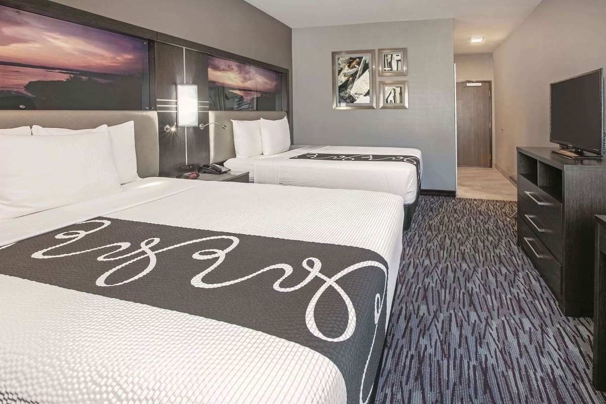 Een hotelkamer met twee bedden, een televisie, een bureau en kunstwerken aan de muur.