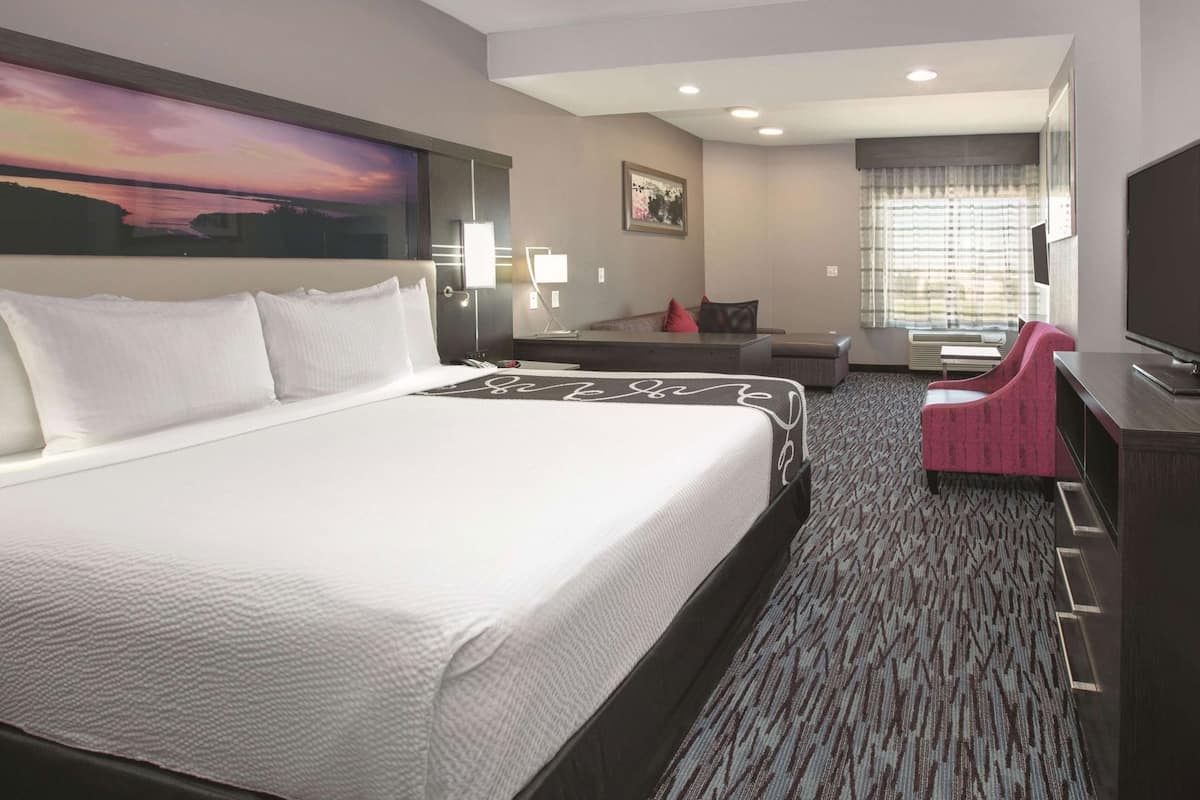 Een hotelkamer met een groot bed, een bureau, een stoel, een televisie en een schilderij aan de muur.
