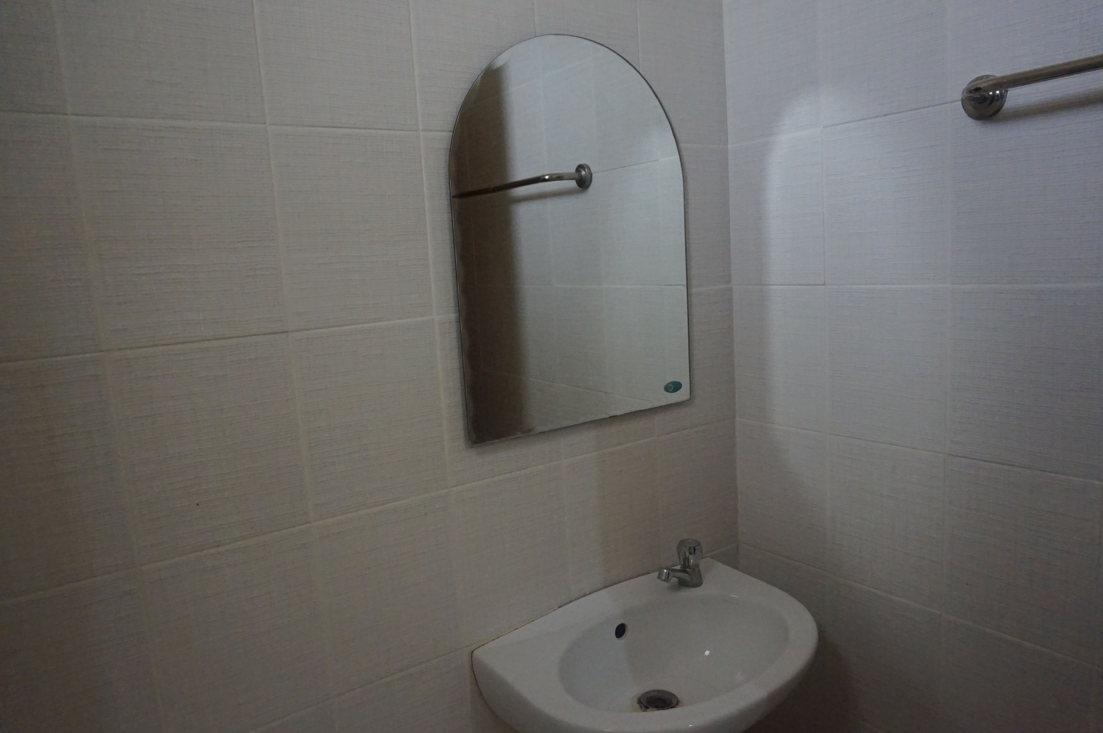 A bathroom with a white sink, a mirror, and a towel rack.