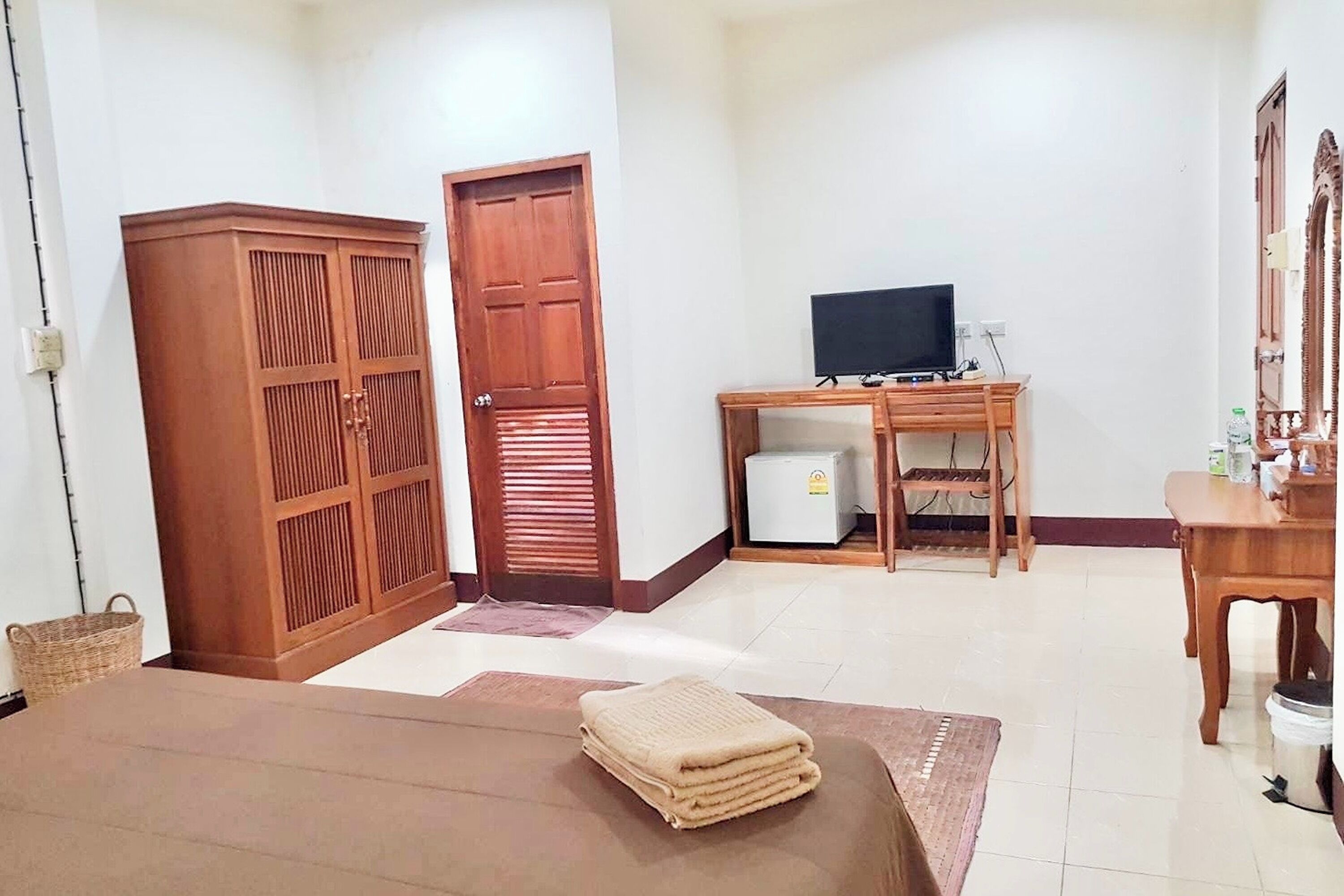Una habitación con una cama, un escritorio con una computadora, un televisor y un armario.