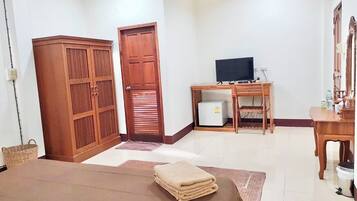 Una habitación con una cama, un escritorio con una computadora, un televisor y un armario.