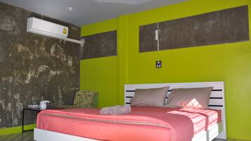 A bedroom with a bed, a nightstand, an air conditioning unit, and a wall with a textured pattern.