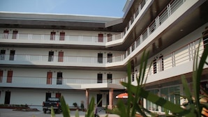 A multi-story hotel with balconies, a covered entrance, and a truck parked in the courtyard. - Grand Perfect Apartment (Udon Thani)