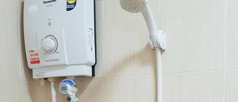 A bathroom with a wall-mounted electric shower, a handheld showerhead, and a bidet.