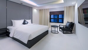 A modern bedroom with a large bed, bedside tables, a small round table, and a chair. - Hotel The Designers Yeouido (Seoul)