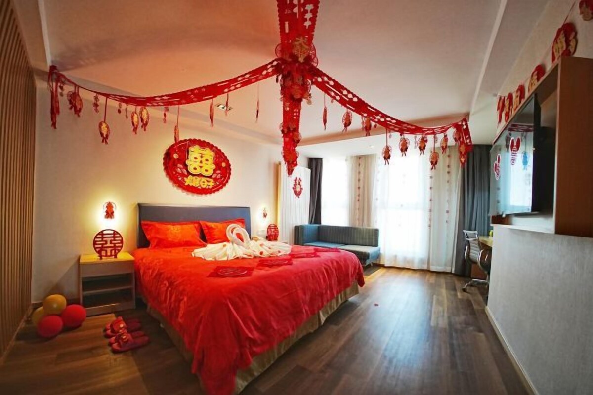 A hotel room with a large bed, a bedside table, a sofa, and a desk.