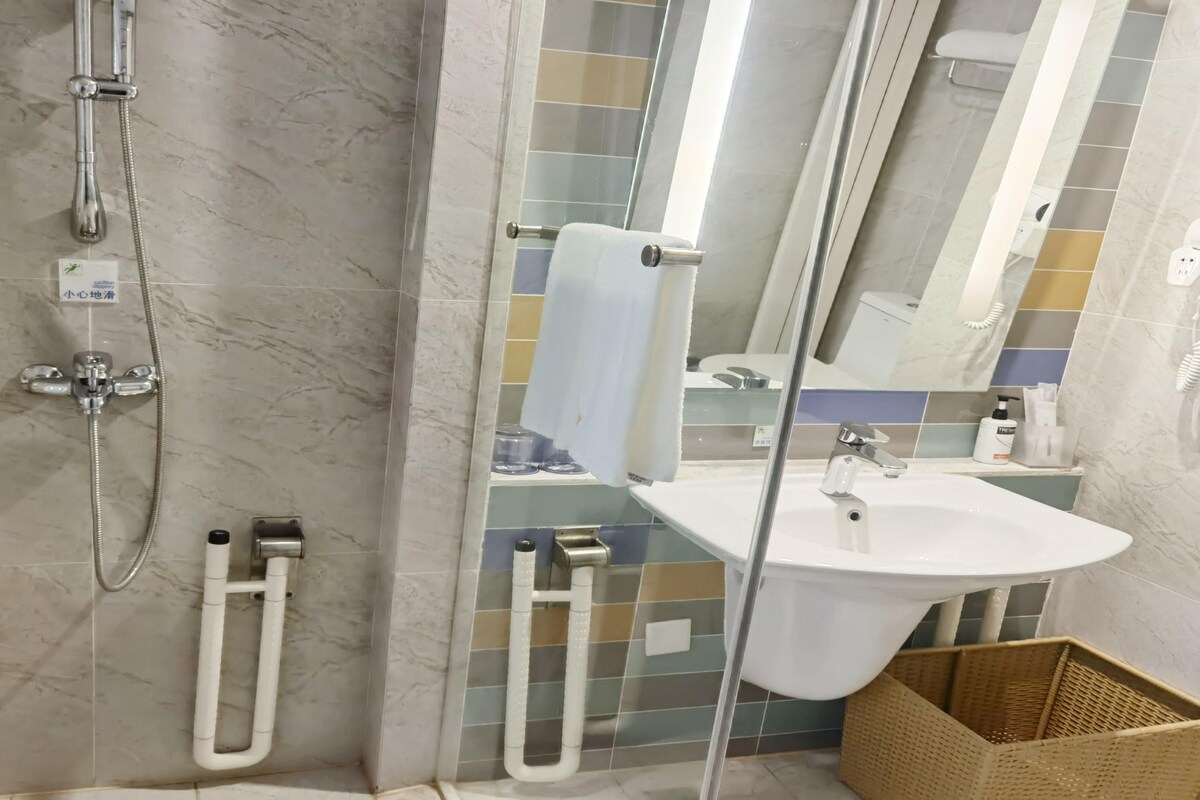 Une salle de bain avec une douche, un lavabo et un miroir.