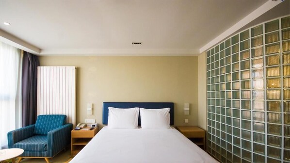 A hotel room with a bed, a blue-striped armchair, a nightstand with a phone, and a wall with a grid pattern. - Holiday Inn Express Zhangjiakou Park View (Zhangjiakou)
