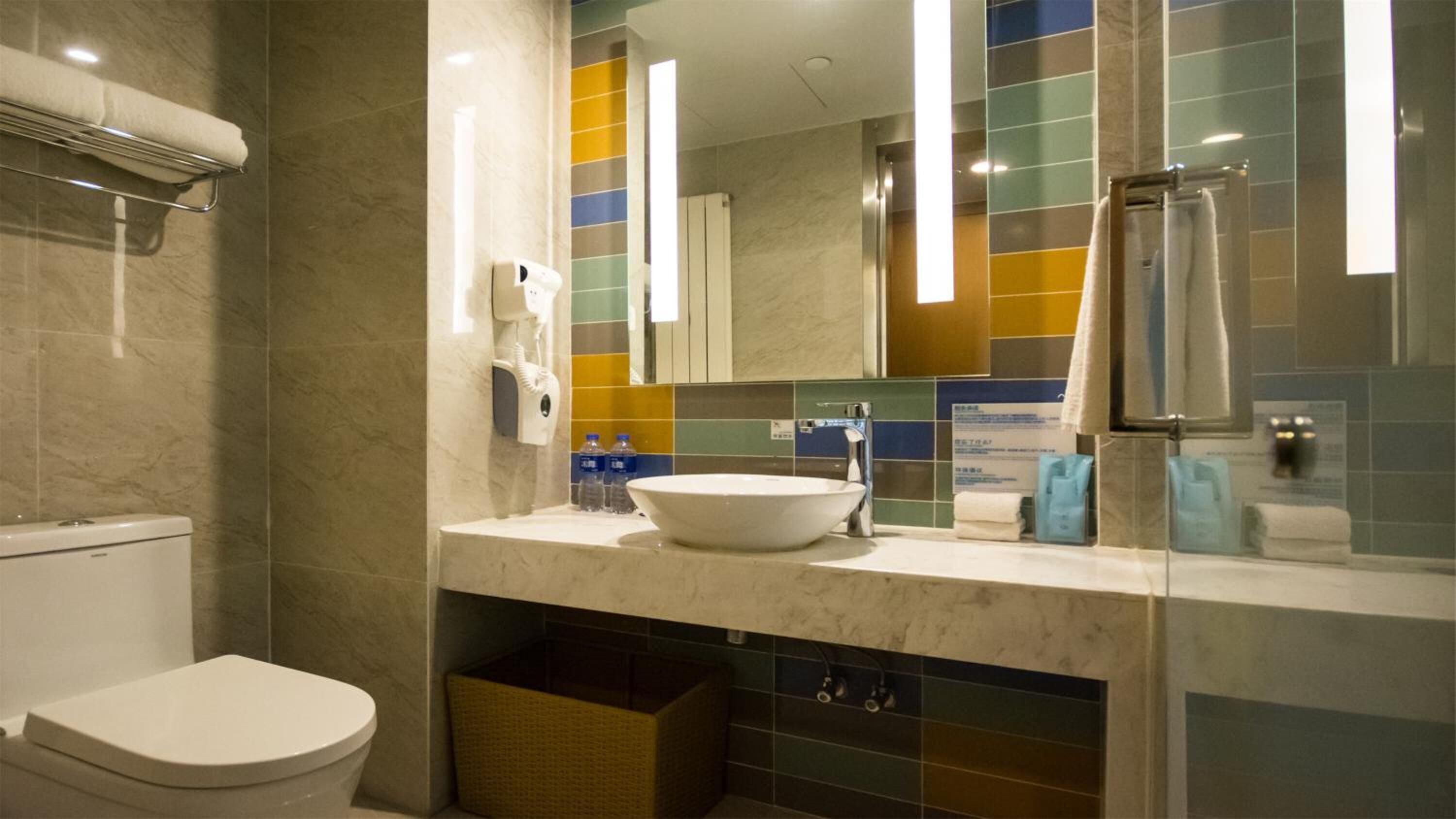 A modern bathroom with a white toilet, a large sink, and a mirror.
