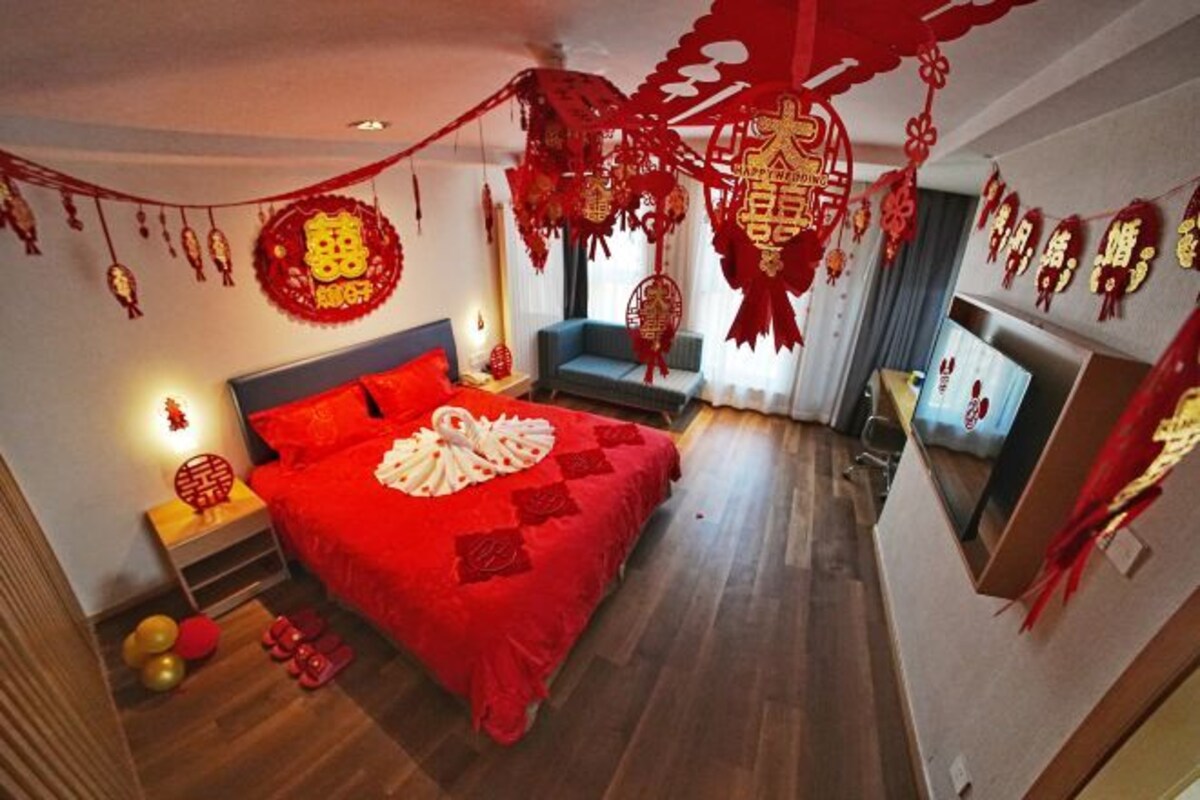 A room with a red bedspread, a blue sofa, and red decorations.