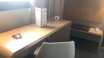 Un espace de bureau moderne avec un bureau en bois, une chaise blanche, un ordinateur de bureau et un petit haut-parleur posé sur le bureau.