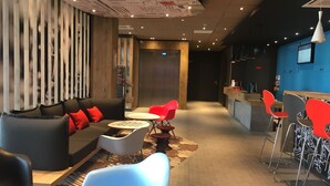 Un espace de détente moderne comprenant un canapé, des fauteuils, une petite table et un comptoir de bar.