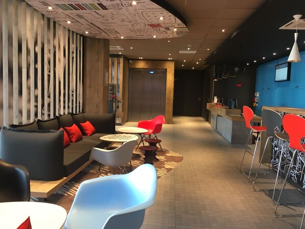 Ein moderner Lounge-Bereich mit einer Couch, Sesseln, einem kleinen Tisch und einer Bar.