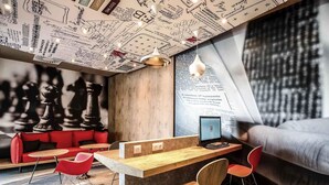 Un intérieur moderne avec un bar en bois, des sièges rouges et un grand échiquier.