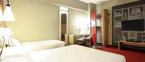 A hotel room with two beds, a desk, a chair, a TV, and a wall with a chalkboard design.