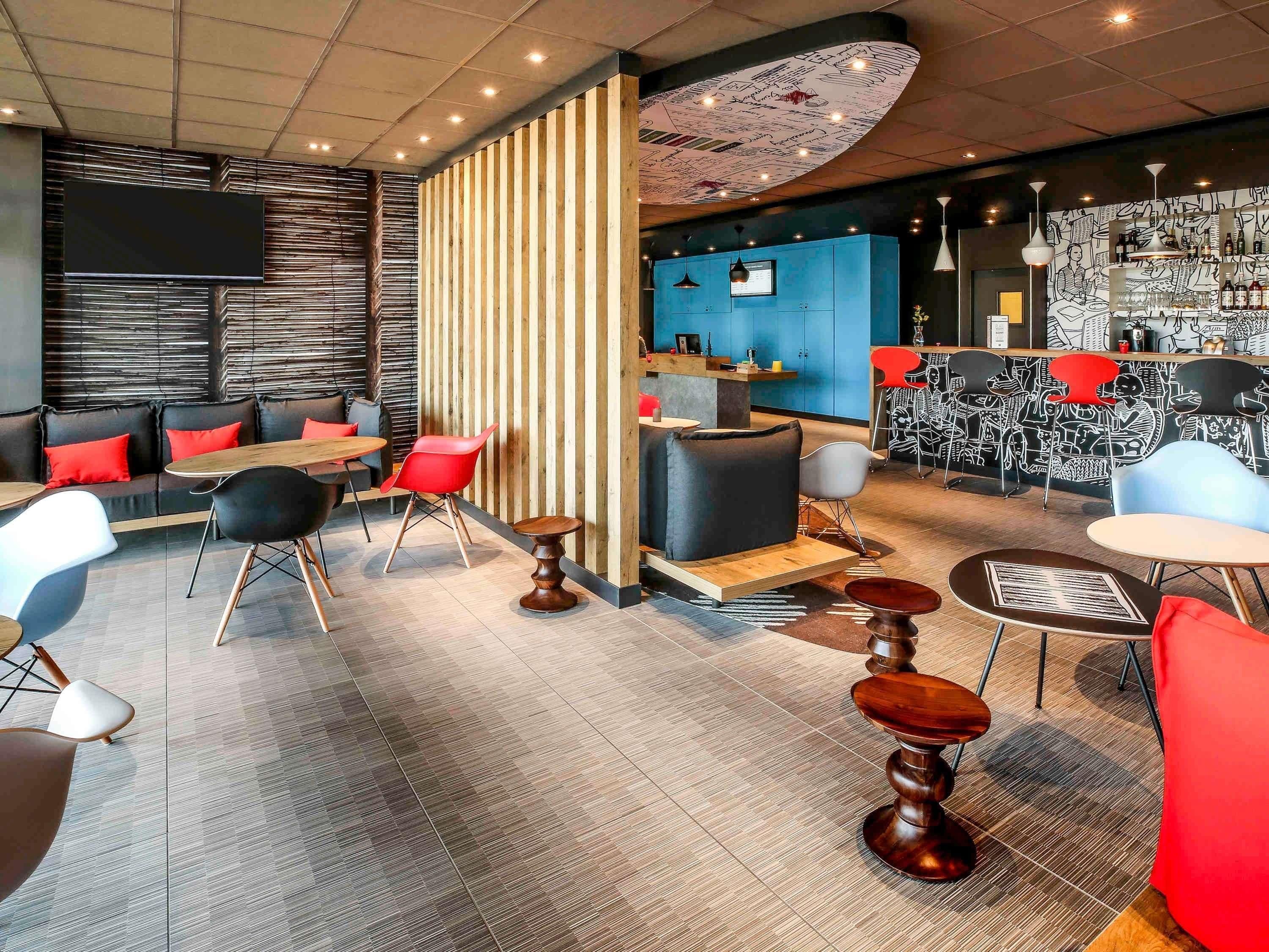 Een modern interieur met een bar, zitgedeelte en een televisiescherm.