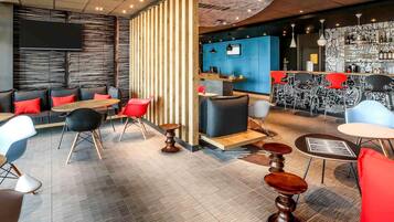 Een modern interieur met een bar, zitgedeelte en een televisiescherm.