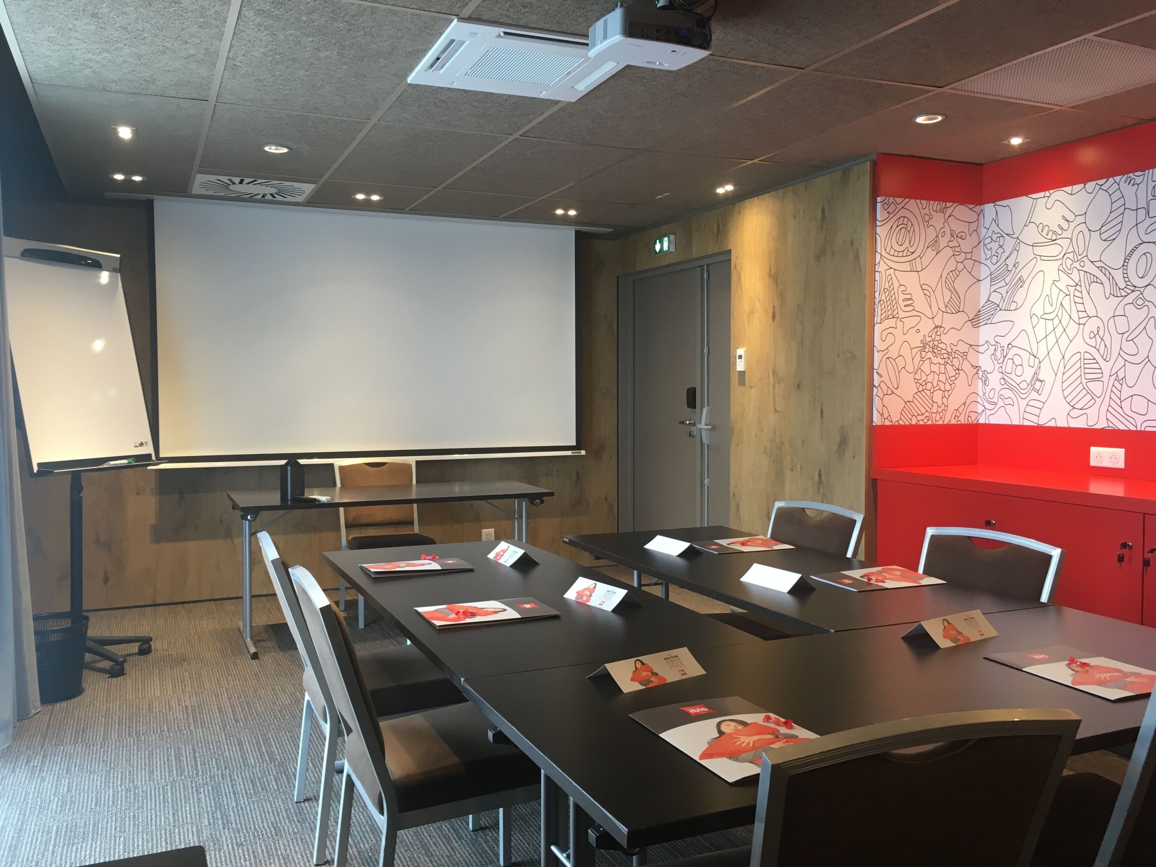 A conference room with a long table, chairs, a projector screen, and a whiteboard.