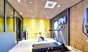 Ein modernes Fitnessstudio mit Laufband, Ergometer und Wasserspender.