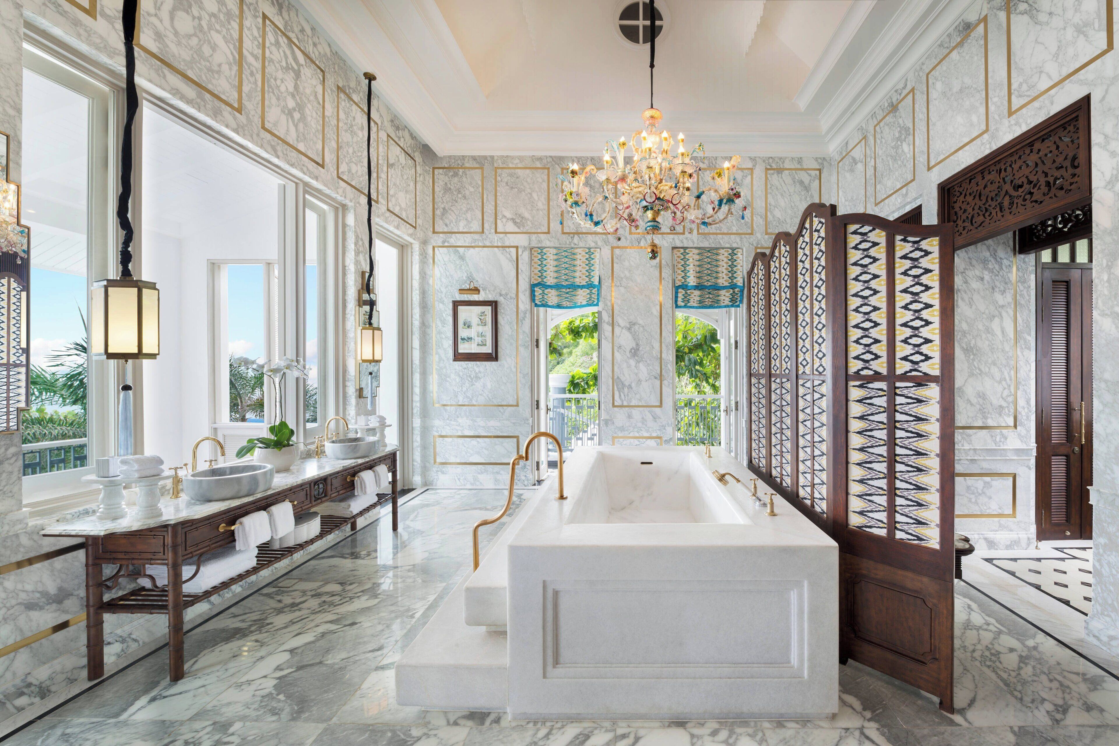 A luxurious bathroom with a large bathtub, two sinks, and a chandelier.