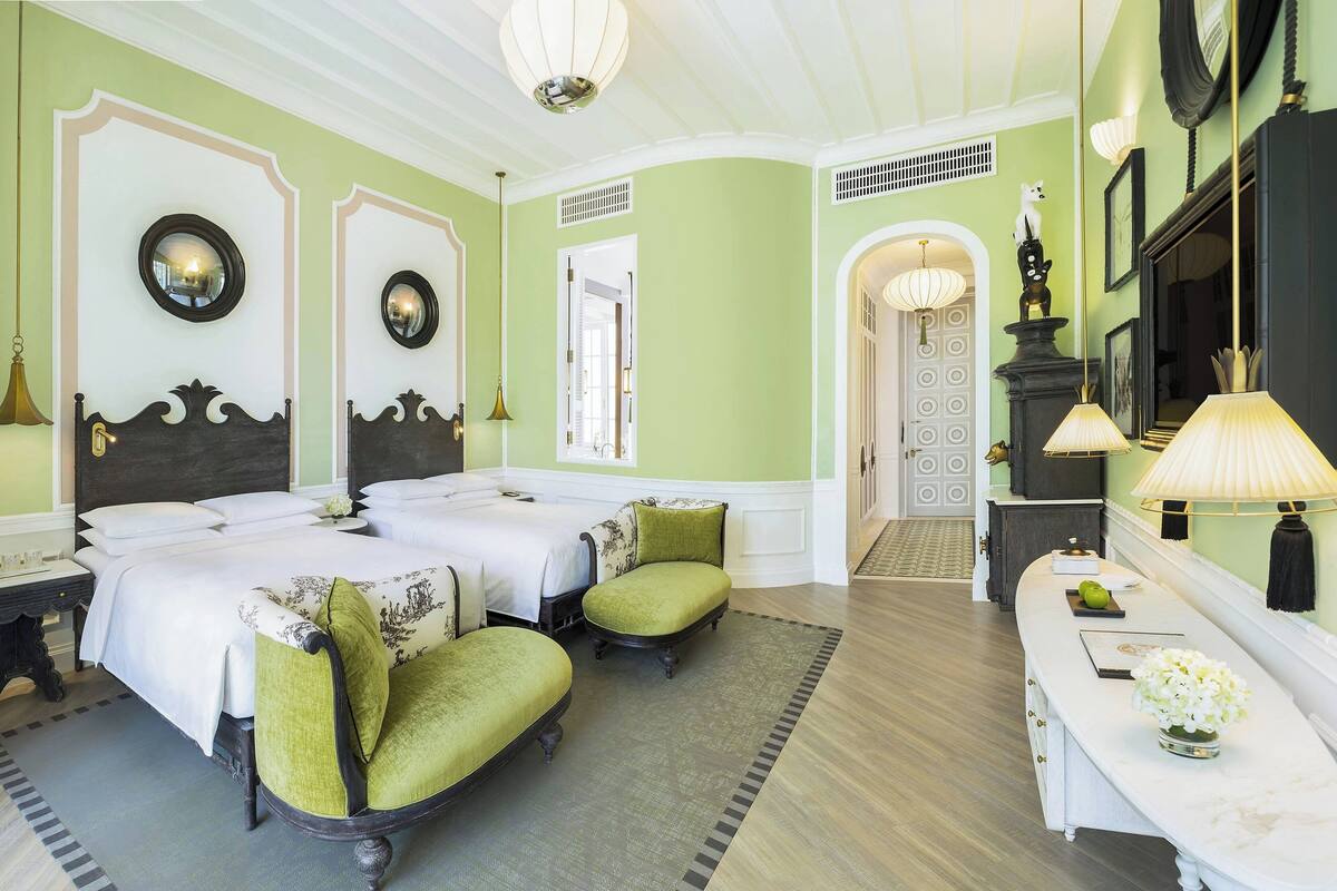 Ein Hotelzimmer mit zwei Betten, einer Sitzecke mit Tisch und einem Spiegel an der Wand.