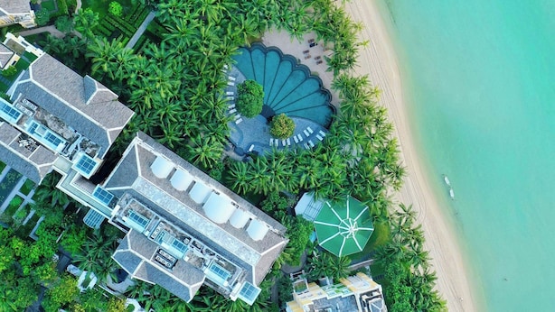Ein Luftbild zeigt ein Resort mit mehreren Gebäuden, einem Schwimmbad und einem Strand.
