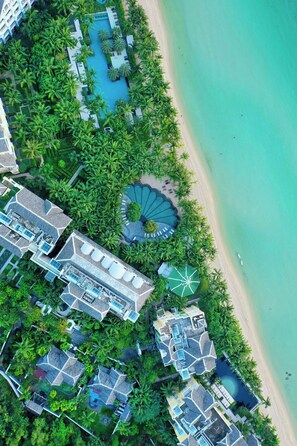 Une vue aérienne d’un complexe hôtelier comprenant plusieurs bâtiments, une piscine et une plage.