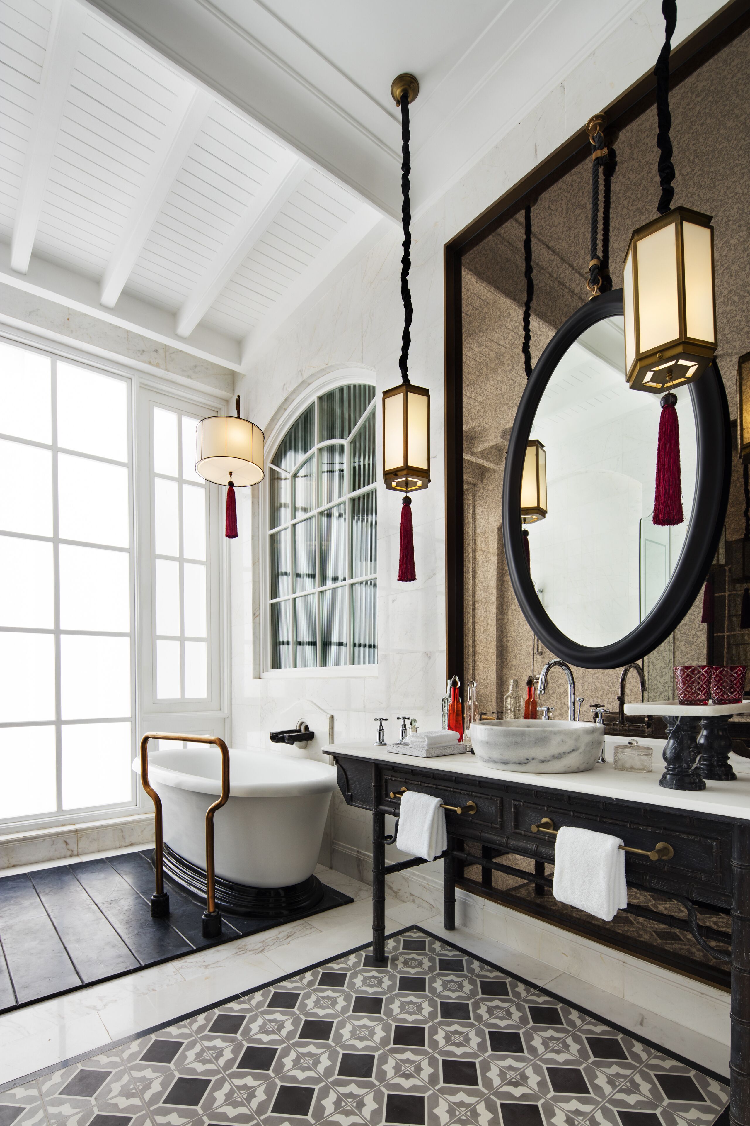 A bathroom with a white bathtub, a large mirror, and two pendant lights.