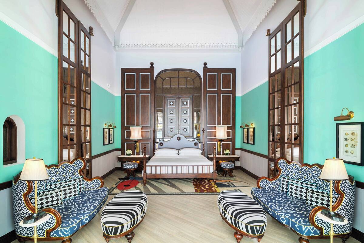Ein Zimmer mit einem großen Bett, zwei Sofas und einem Spiegel an der Wand.