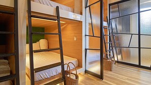 Een slaapkamer met een stapelbed, een raam met uitzicht en een mand.