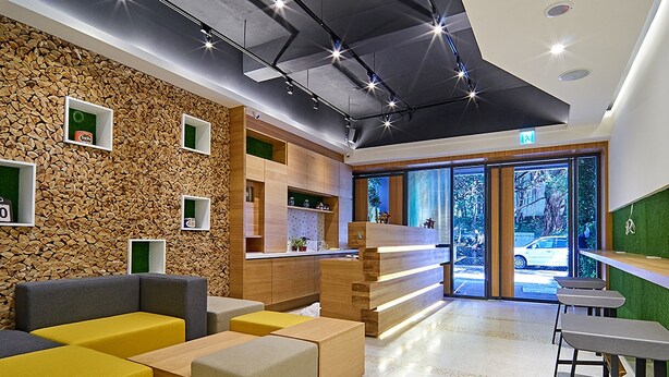 Een moderne lobby met een stenen muur, zithoeken, een receptiebalie en grote ramen.