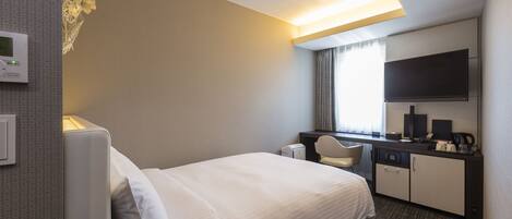 A hotel room with a bed, a desk with a chair, a television, and a coffee maker.