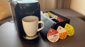 A coffee maker with a cup and a box of tea pods.
