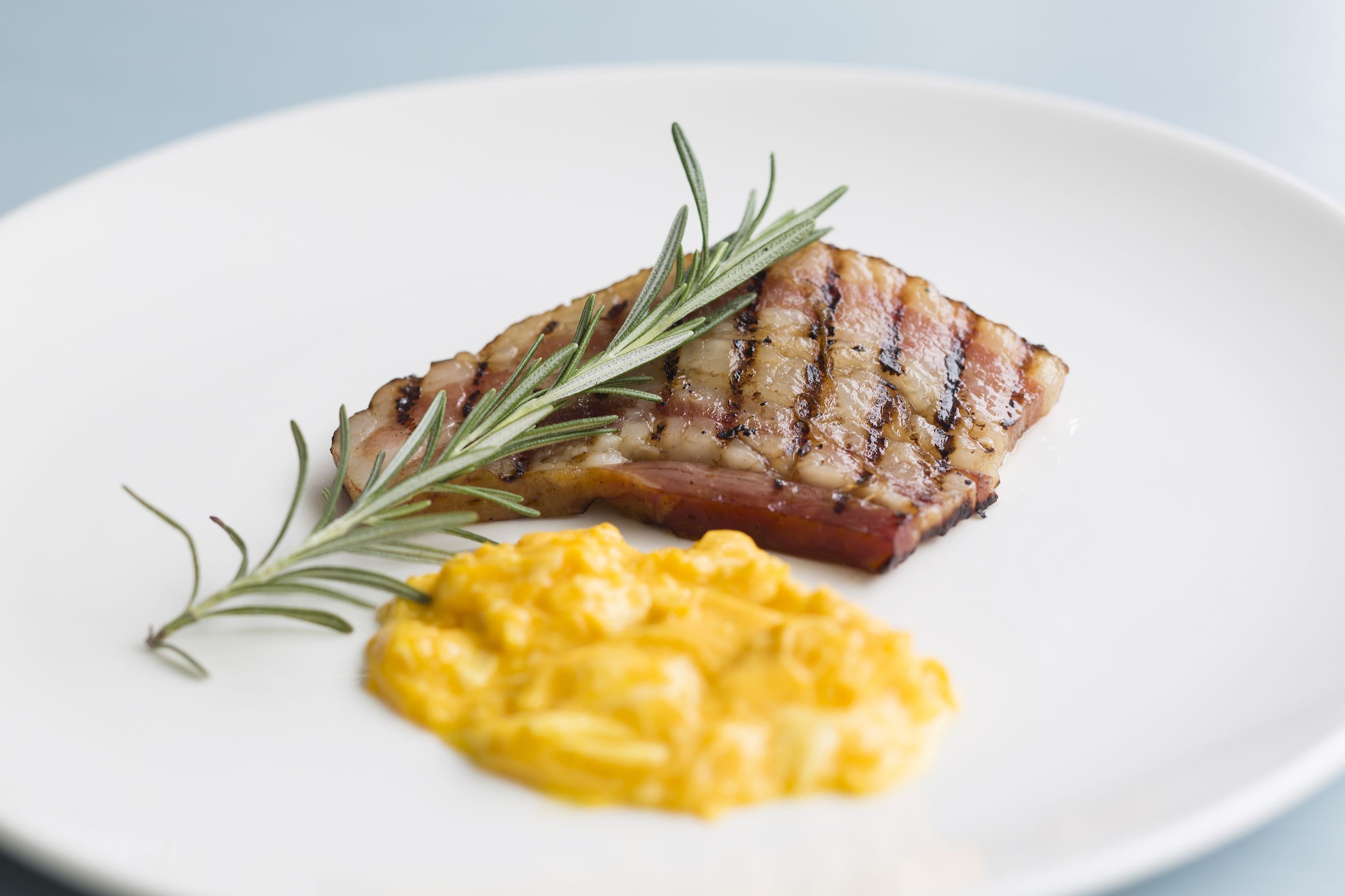 Ein Teller mit gegrilltem Steak und Rührei, garniert mit Rosmarin.