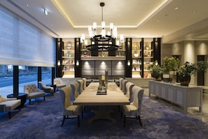 Une salle à manger spacieuse avec une longue table, des sièges confortables et un lustre décoratif.