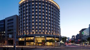Un hotel de varios pisos con fachada curva, ventanas amplias y una entrada destacada.