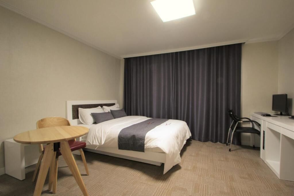 Una habitación de hotel con cama, escritorio, silla y una pequeña mesa.