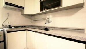 A compact kitchen with white cabinets, a granite countertop, a stainless steel sink, and a built-in microwave.